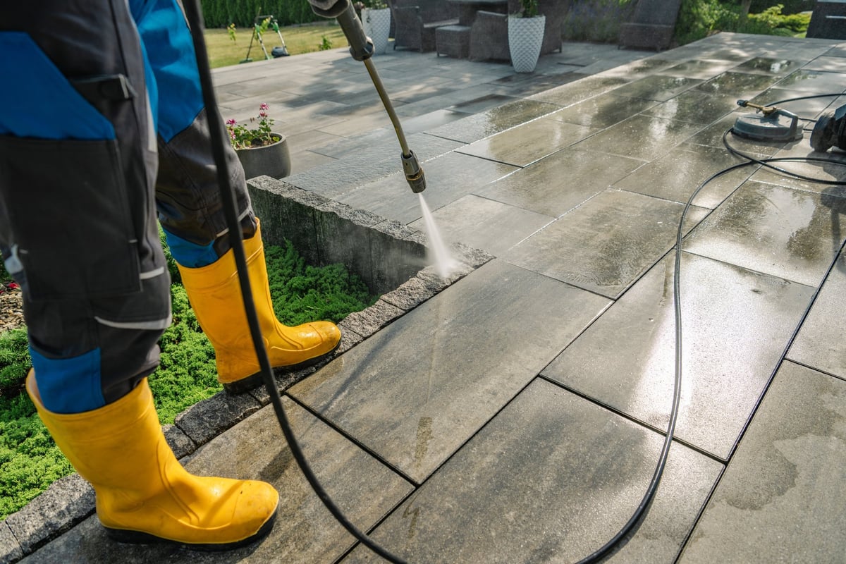 Professional pressure washer cleaning a stone patio